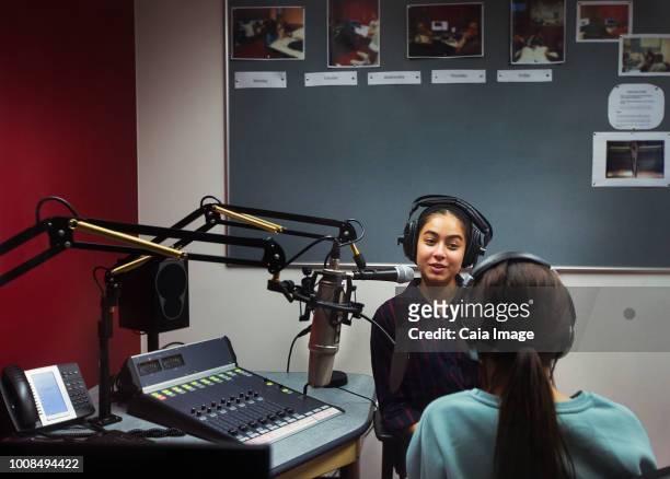 Teenage girl musicians recording music, singing in sound booth