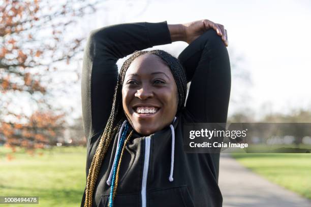 Portrait confident female runner stretching arms in park