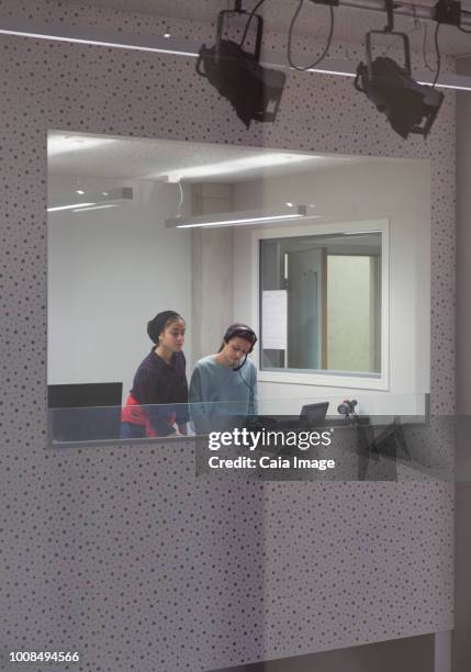 Teenage girl musicians recording music in sound booth