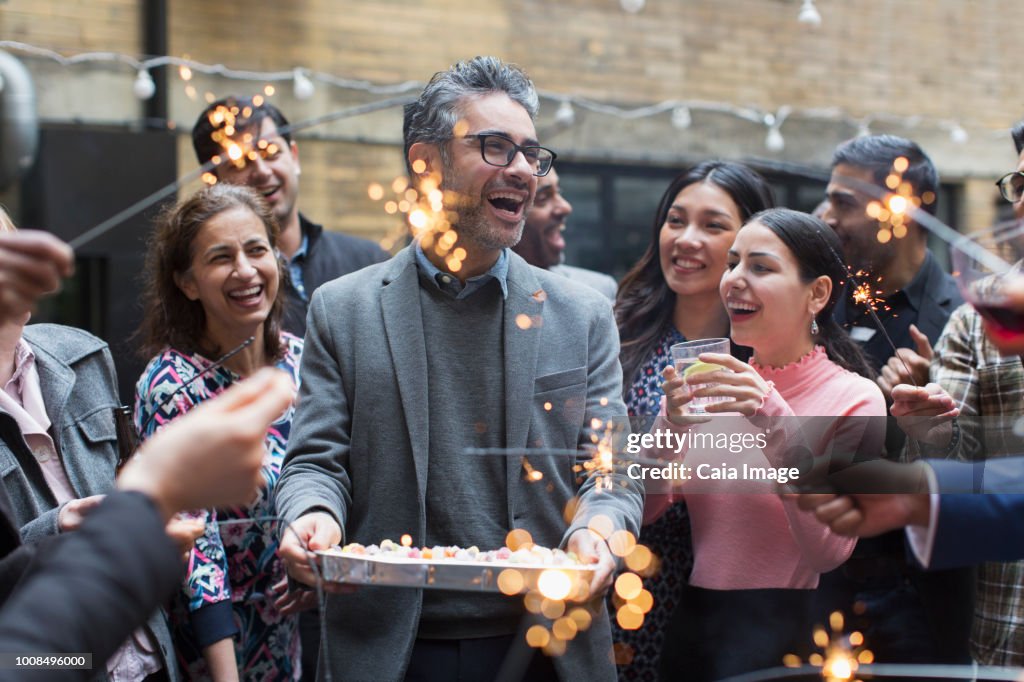 Friends celebrating birthday with cake and sparklers