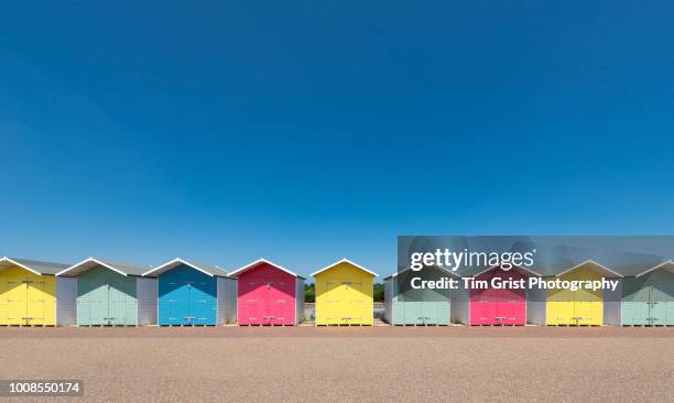 a row of multi-coloured beach huts - beach hut fotografías e imágenes de stock