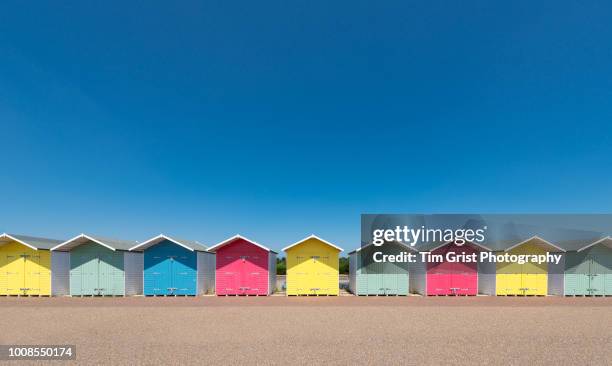 a row of multi-coloured beach huts - beach hut stock pictures, royalty-free photos & images