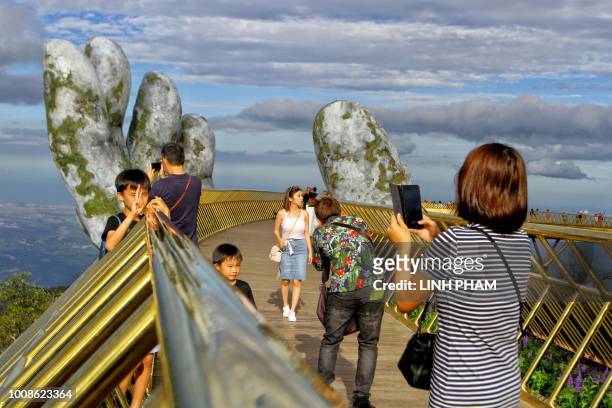In this photograph taken on July 31 visitors pose and take pictures as they walk along the 150-meter long Cau Vang "Golden Bridge" in the Ba Na Hills...