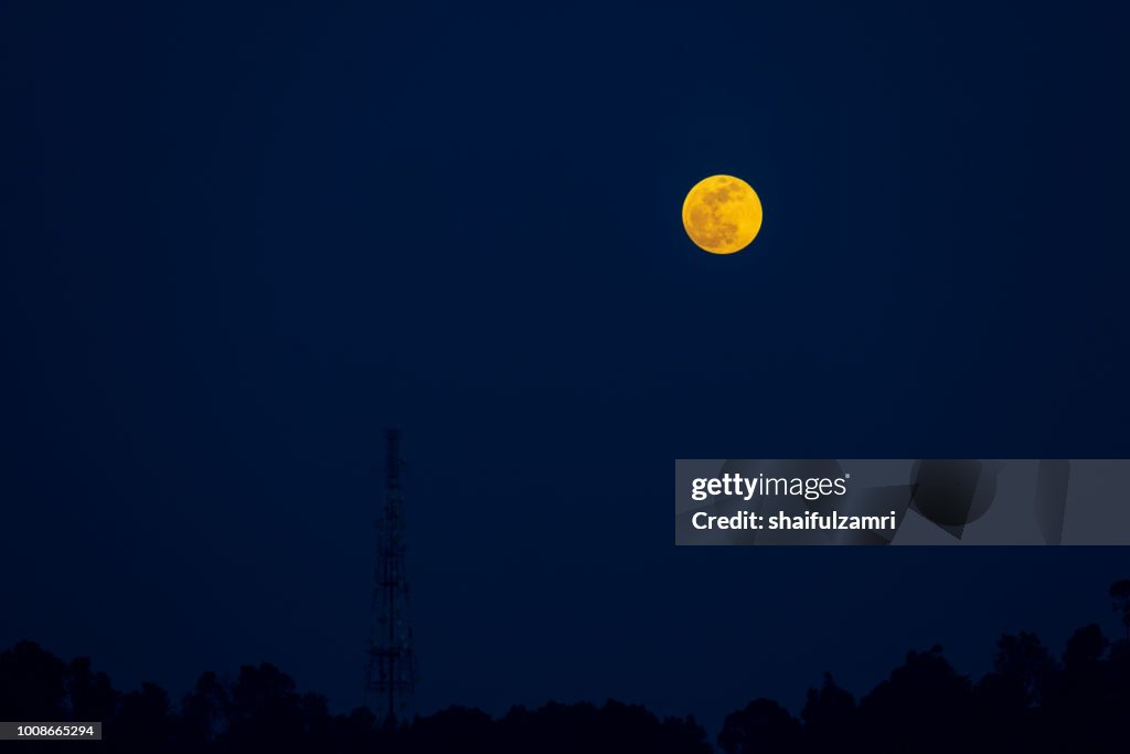 Full moon rise over telecommunication tower