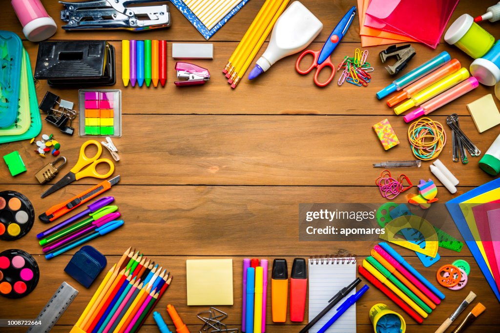 Overhead shot of wood table with frame of school office supplies