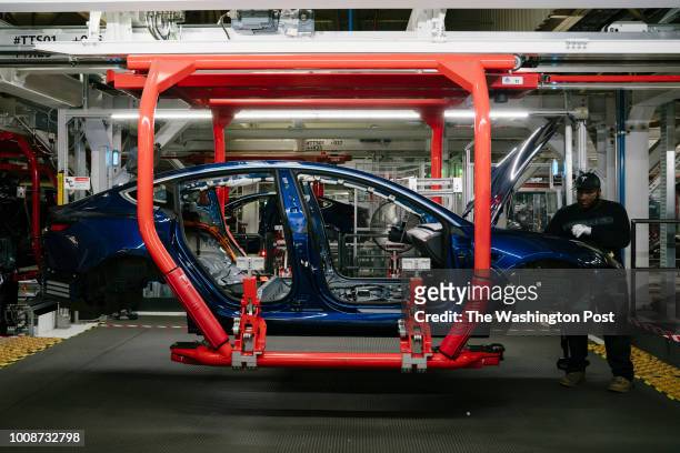 Paul Jacob works on the general assembly of the Tesla Model 3 at the Tesla factory in Fremont, California, on Thursday, July 26, 2018.