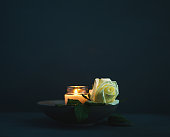 Burning candle with white rose in remembrance