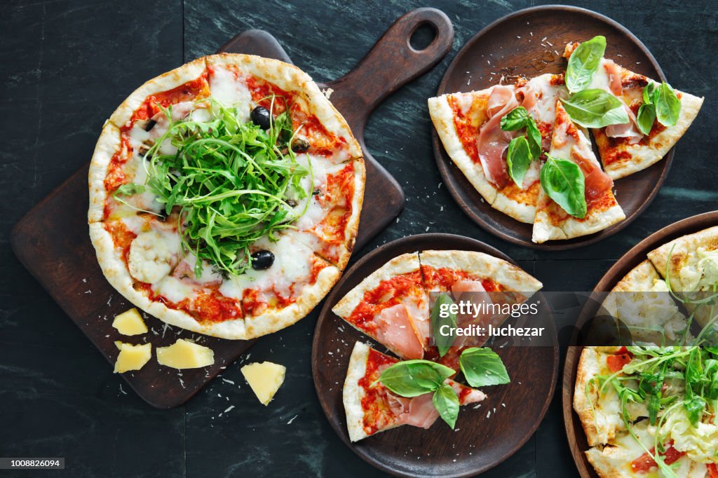 Pizza with ham, olive and arugula