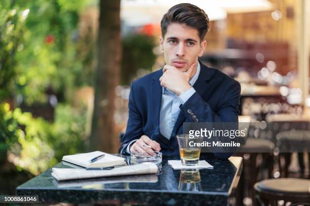 depressed man smoking cigarette and drinking whiskey at the bar - substance abuse programs stock pictures, royalty-free photos & images