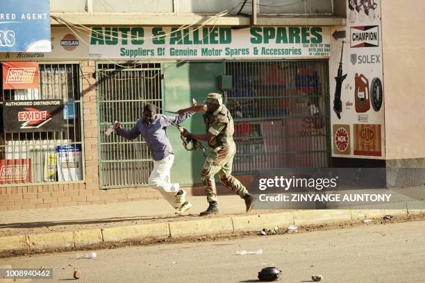 Zimbabwean soldier beats a man in a street of Harare on August 1, 2018 as protests erupted over alleged fraud in the country's election. One man was...