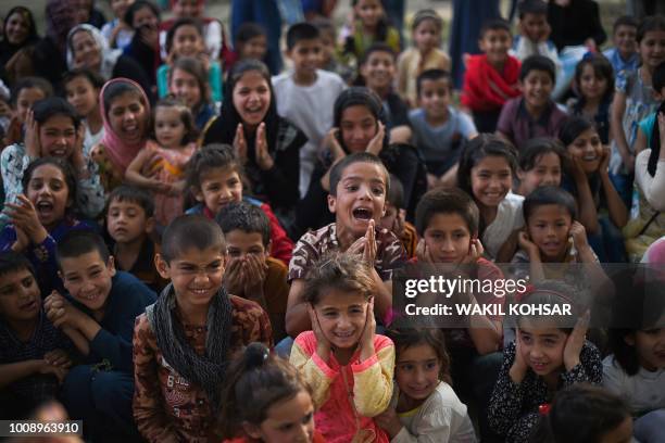 Afghan children cheer and react as they watch a performance of The Mobile Mini Circus for Children at the Bagh-e-Babur Garden, in Kabul, on August 1,...