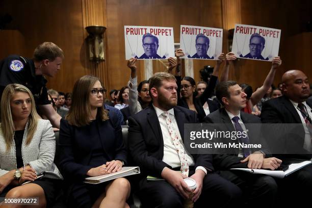 Protesters hold up signs during the testimony of Acting EPA Administrator Andrew Wheeler before the Senate Environment and Public Works Committee...