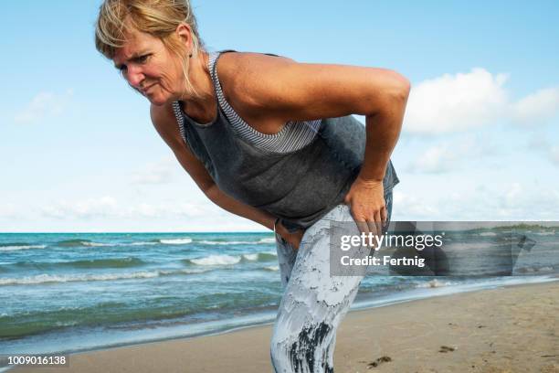 a mature woman in her fifties experience hip pain during a morning run - hips stock pictures, royalty-free photos & images