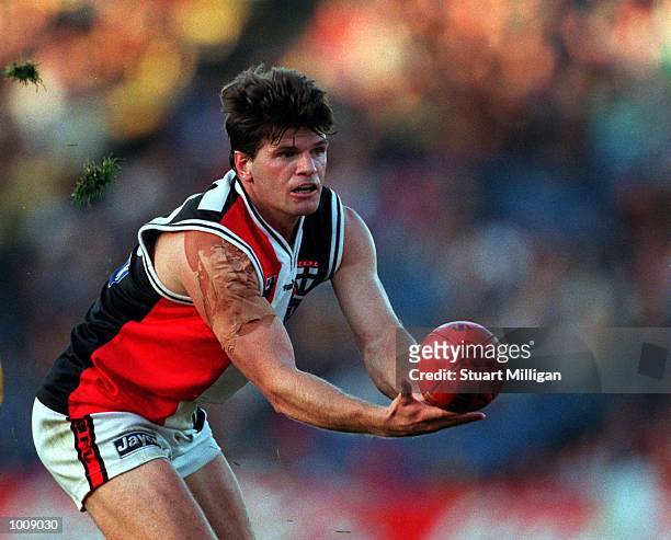 Robert Harvey, number 35 for St Kilda passes off a handball, as the turf from the playing surface flys through the air, during the match between...