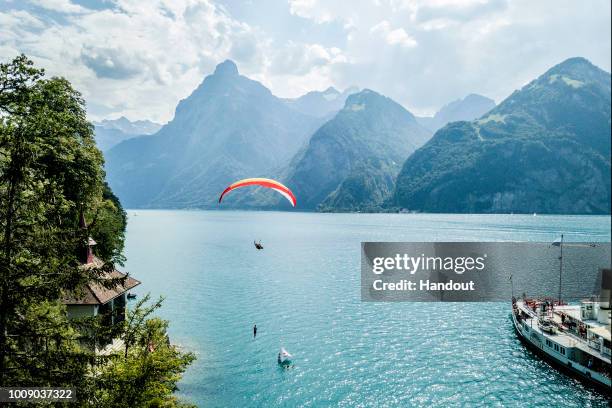 In this handout image provided by Red Bull, David Colturi of the USA dives from the paraglider of Christian "Chrigel" Maurer of Switzerland in front...