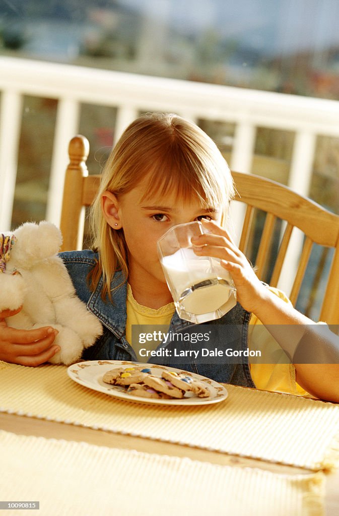 YOUNG GIRL EATING COOKIES AND MILK