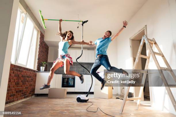 happy couple cleaning their new home - woman cleaning for man stock pictures, royalty-free photos & images