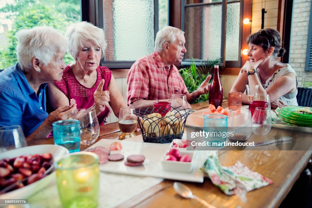 Group of seniors having dinner in summer house.