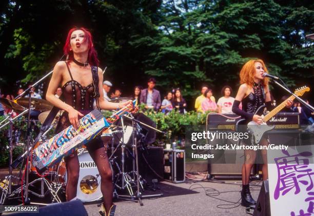 Japanese J-rock musician Devil plays keyboard guitar with her band, Jaco:neco, in Yoyogi Park in Harajuku, Tokyo, Japan, May 22, 1994. Also visible...