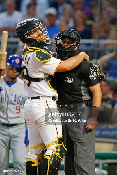 Francisco Cervelli of the Pittsburgh Pirates prevents home plate umpire Chris Guccione from falling over after taking a foul ball to the mask in the...
