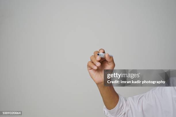 hand holding blue marker against white wall with copy space - hand marker stock pictures, royalty-free photos & images