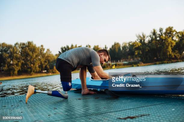 Amputee sportsman adjusting his kayak for training