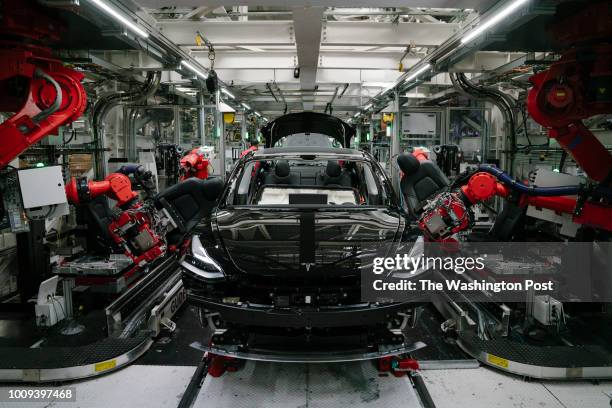 Robotics arms install the front seats to the Tesla Model 3 at the Tesla factory in Fremont, California, on Thursday, July 26, 2018.