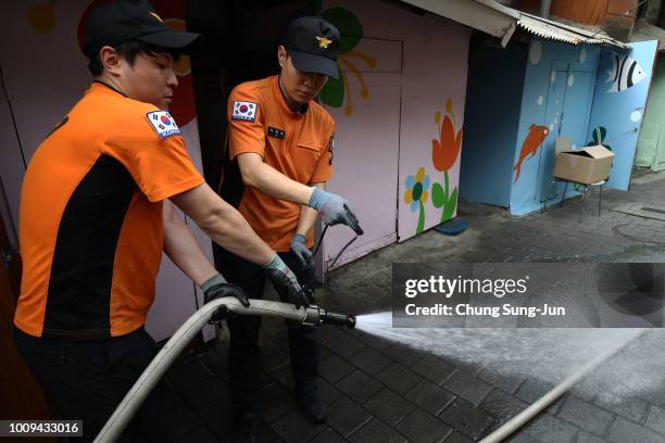 Firefighters spray water in an alley of a slum area on August 2, 2018 in Seoul, South Korea. South Korea grappled with a heat wave in recent weeks...