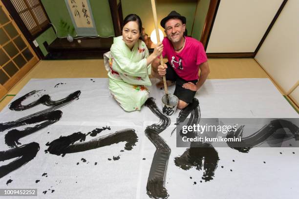 caucasian man enjoys japanese calligraphy - washitsu stock pictures, royalty-free photos & images