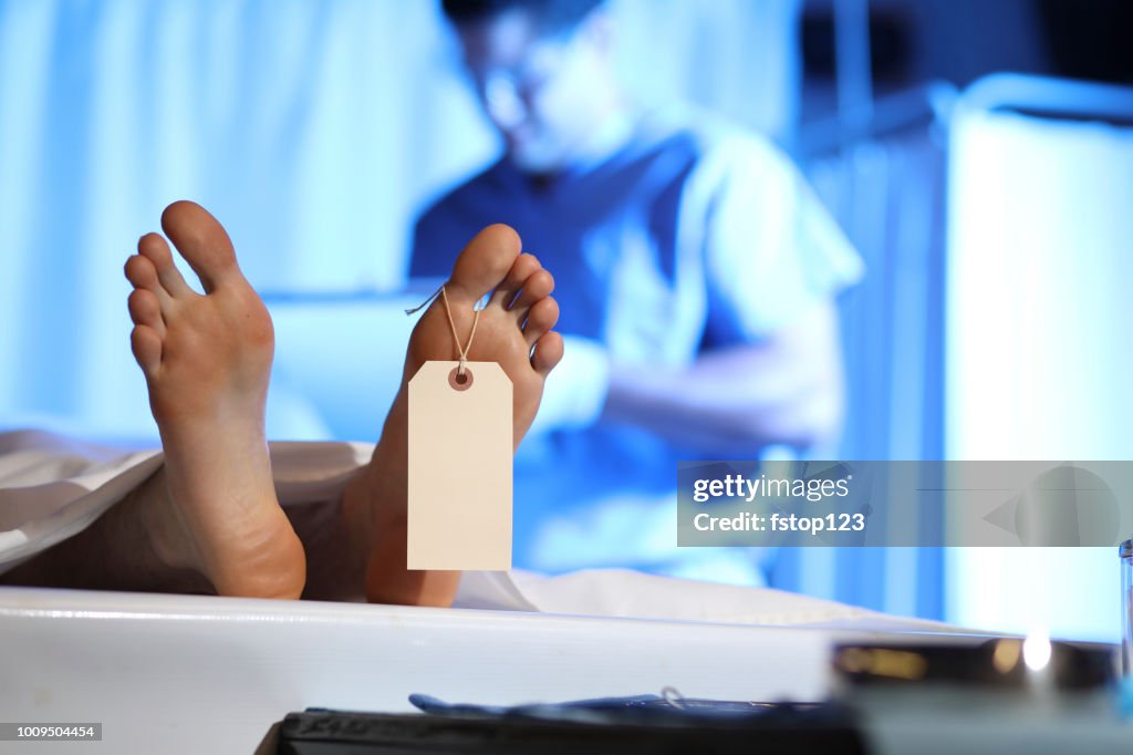 Medical Examiner with corpse in morgue.
