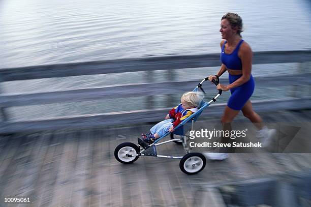 2 yr. old boy and mom running with stroller - jogging stroller stockfoto's en -beelden
