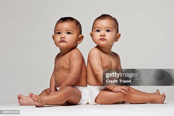 baby twins, boy and girl sitting back to back - side by side stock pictures, royalty-free photos & images