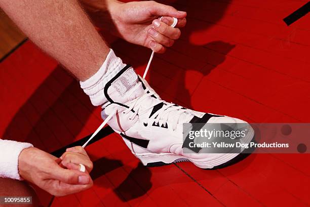 basketball player tying sneakers - basketball shoe stock-fotos und bilder