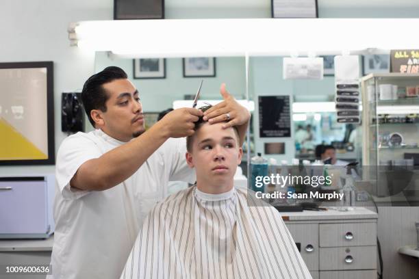 Boy getting hair styled at barber