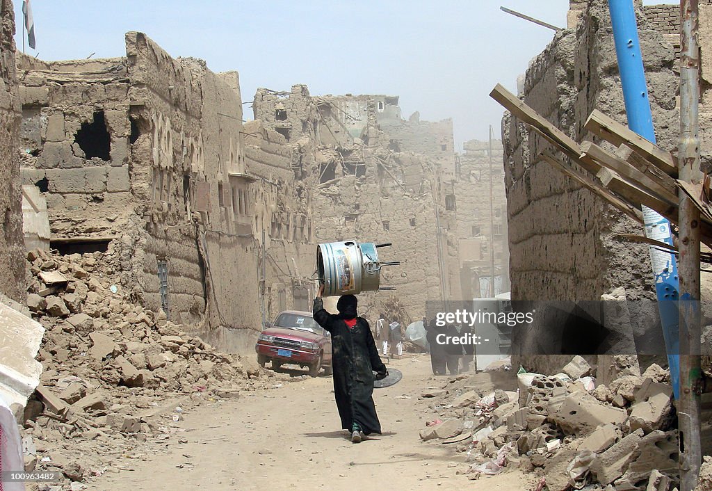 A Yemeni woman walks through a heavily d