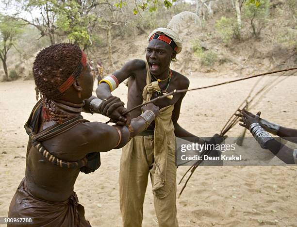 Woman of the Hamar Tribe struggles with a village chief to take back willow sticks she wants to be whipped with during a wedding celebration near the...