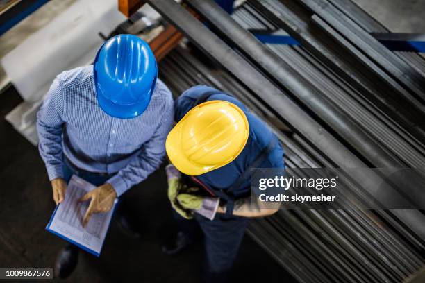 arriba vista de gestor y trabajador manual lectura de informes en el molino de acero. - siderurgicas fotografías e imágenes de stock