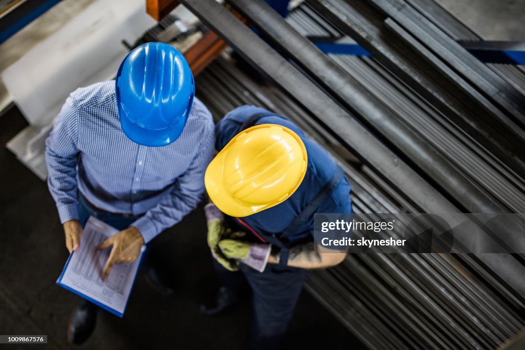 Acima vista do gestor e trabalhador manual ler relatórios na fábrica de aço.