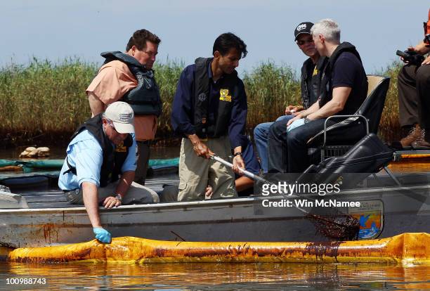 Louisiana Governor Bobby Jindal scoops crude oil from the water during a tour of areas where oil has come ashore with Plaquemines Parish President...