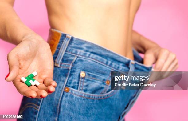 woman showing weight loss and holding diet pills - high waist stockfoto's en -beelden