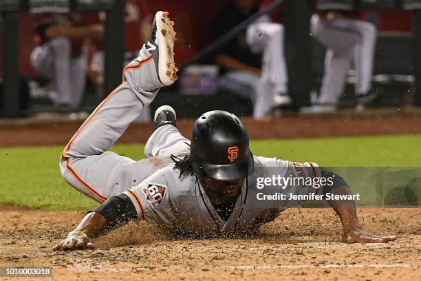 Alen Hanson of the San Francisco Giants safely slides into home plate to score against the Arizona Diamondbacks in the eighth inning of the MLB game...