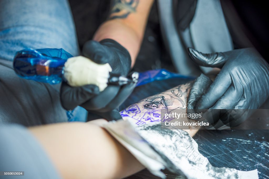 Nahaufnahme der Tätowierer eine Tattoo am Arm einer Frau zu tun