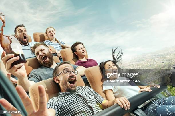 de gelukkige emoties van mannen en vrouwen hebben goede tijd op een achtbaan in het park - amusement park ride stockfoto's en -beelden