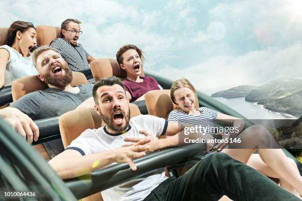 the happy emotions of men and women having good time on a roller coaster in the park - coaster stock pictures, royalty-free photos & images