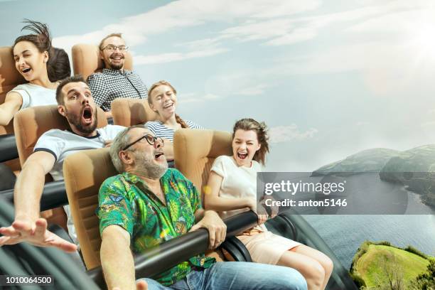 the happy emotions of men and women having good time on a roller coaster in the park - fairground ride stock pictures, royalty-free photos & images