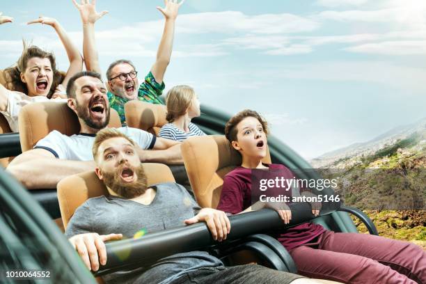 the happy emotions of men and women having good time on a roller coaster in the park - rollercoaster stock pictures, royalty-free photos & images