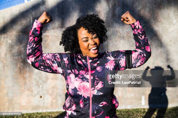 lustiges porträt einer jungen schwarzen, geschwungenen frau während einer trainingseinheit - motivation stock-fotos und bilder