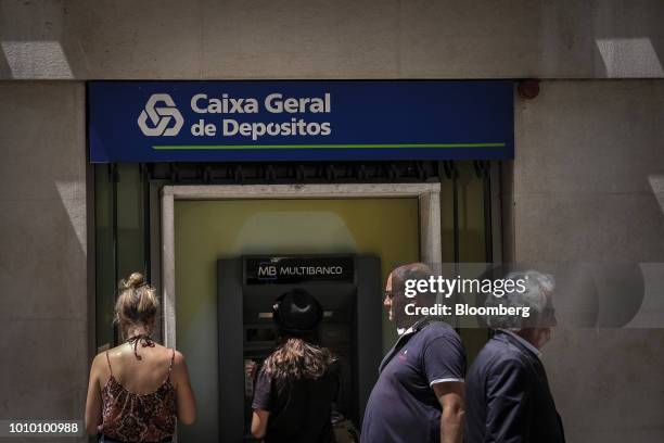 People stand at an automated teller machine , outside a Caixa Geral de Depositos SA bank branch, in the Baixa district of Lisbon, Portugal, on...