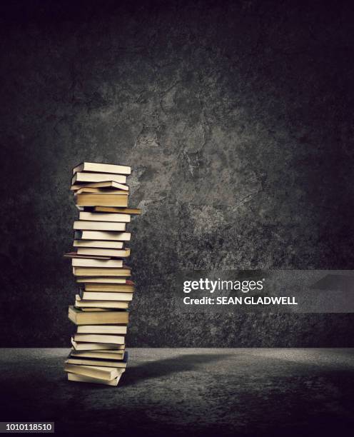 book tower in dark room - books pile stock pictures, royalty-free photos & images
