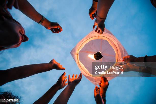 friends lighting up a paper lantern at party - lanterna chinesa imagens e fotografias de stock